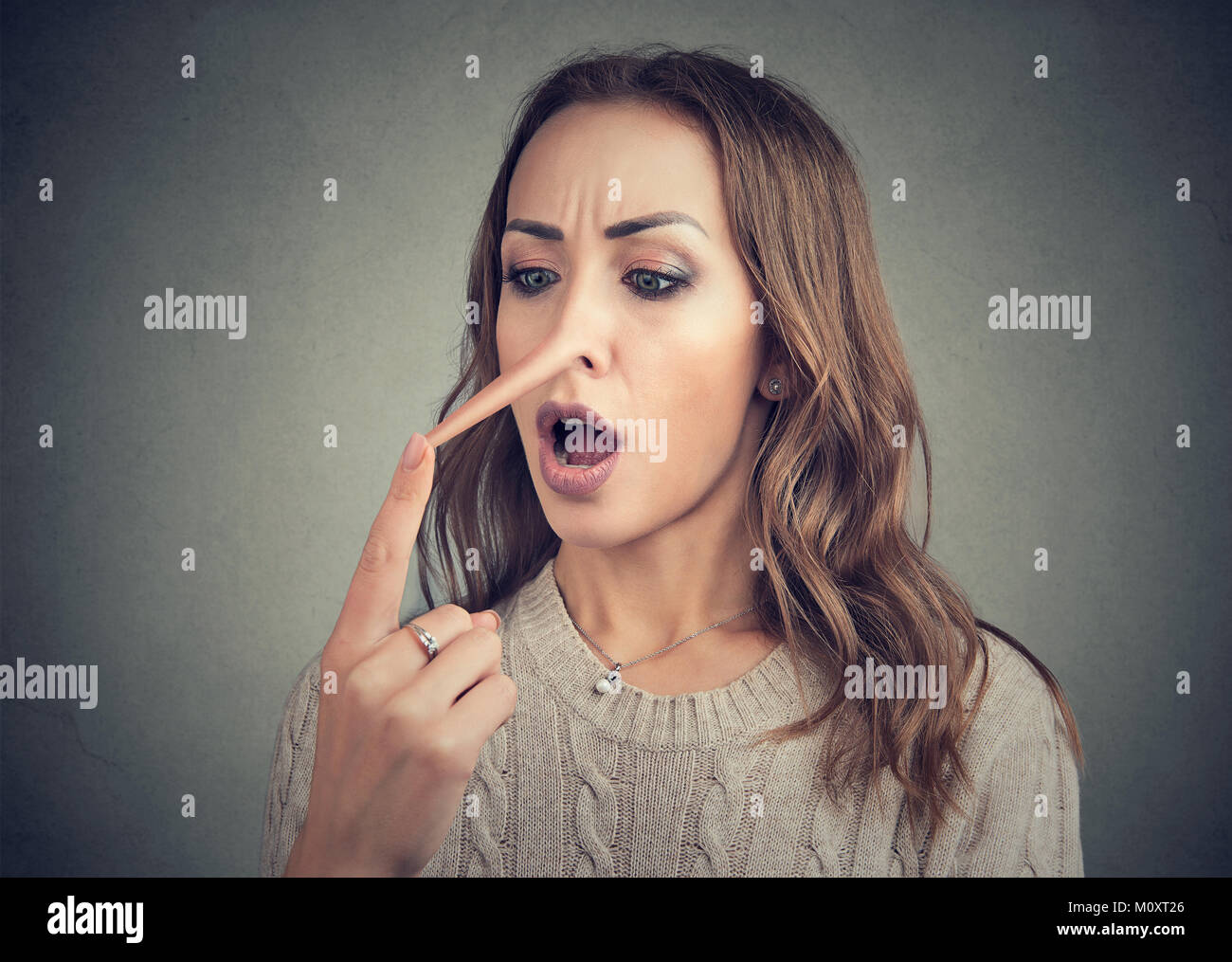 Junge casual Frau berühren verlängerte Nase der Lügner geschockt. Stockfoto