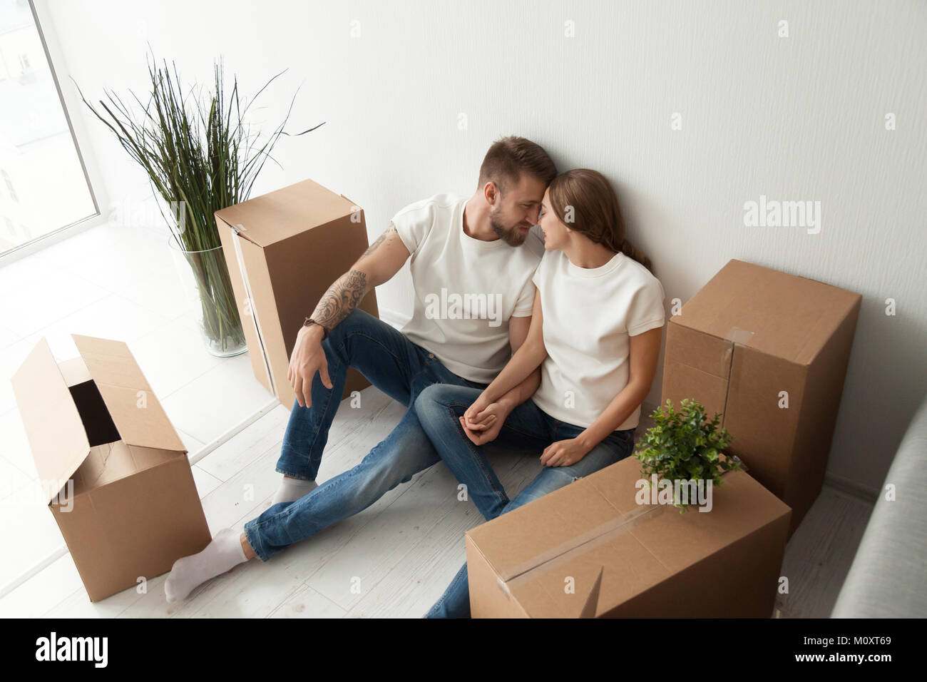 Junges Paar bonding sitzen auf dem Boden mit beweglichen Kästen Stockfoto