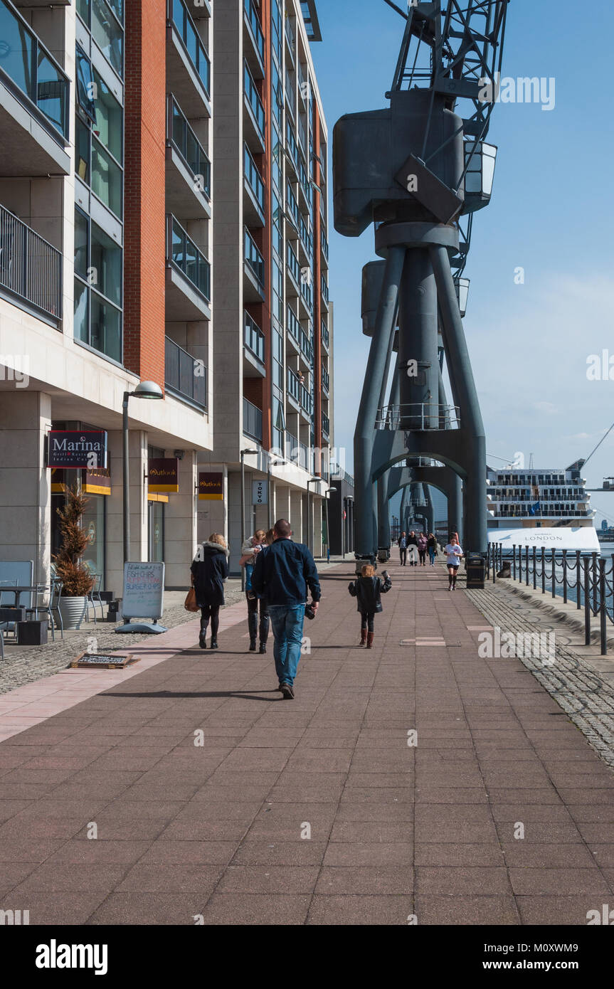 Leute entlang der Uferstraße am Royal Victoria Dock, East London bummeln. Stockfoto