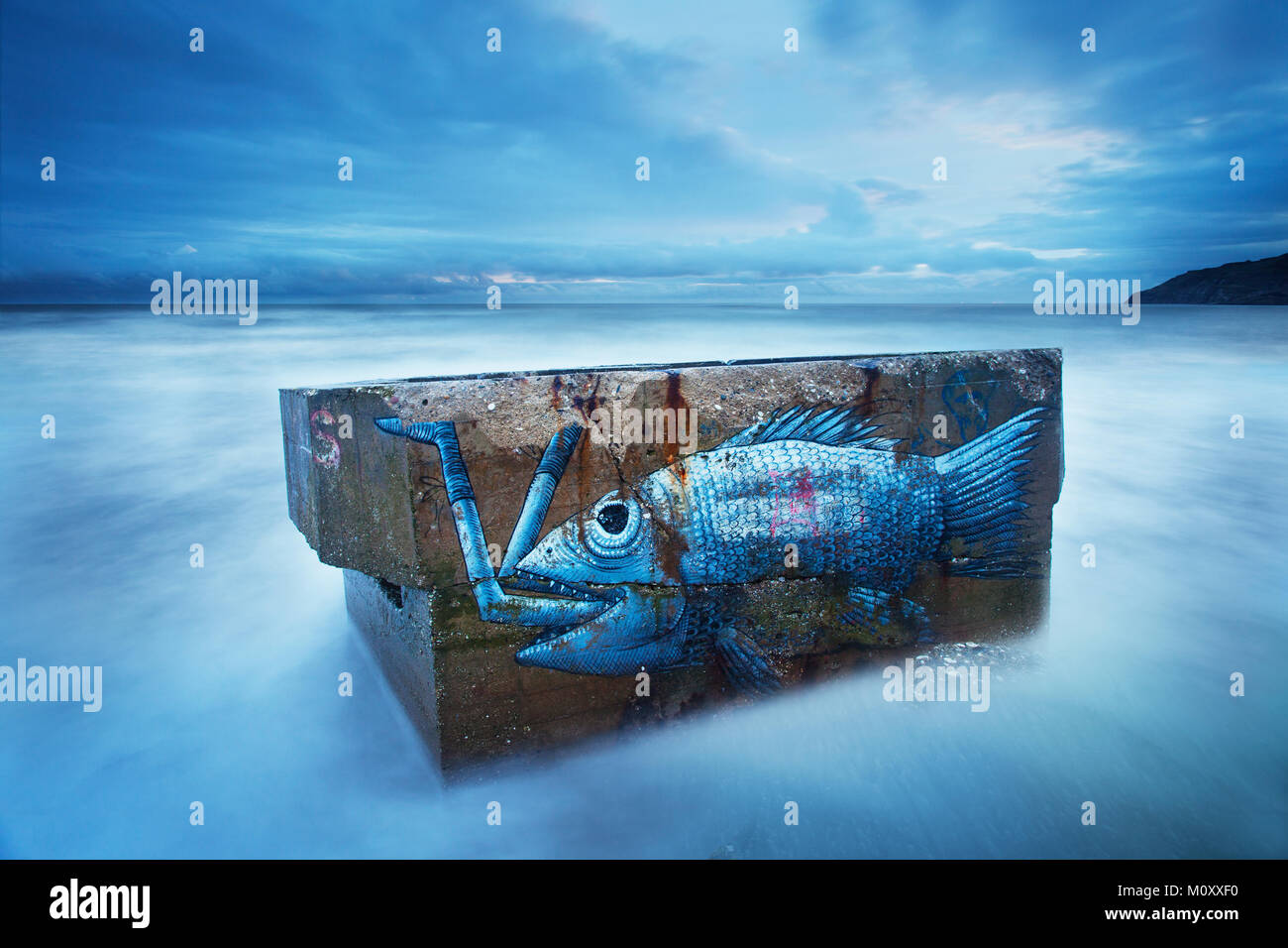 Ein Graffiti Fisch auf einer Pillenschachtel auf Cayton Bay bei Flut mit dem Meer Läppen der Pille. Lange Belichtung. Stockfoto