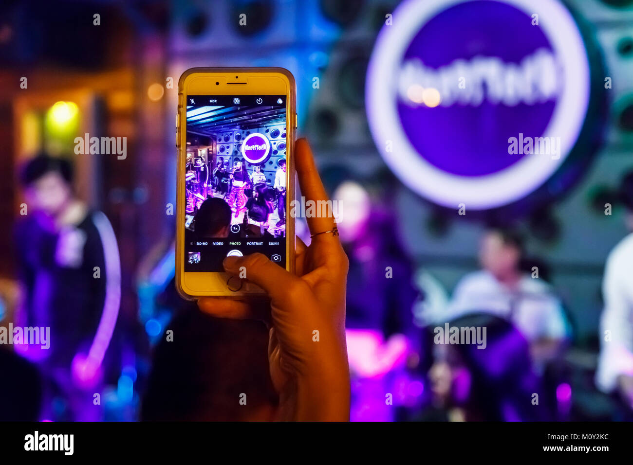 Frau über ein Mobiltelefon (Handy, Smartphone, Handy} ein Bild von einem Rock Band in einem Nachtclub, Saigon (Ho Chi Minh), Vietnam Stockfoto