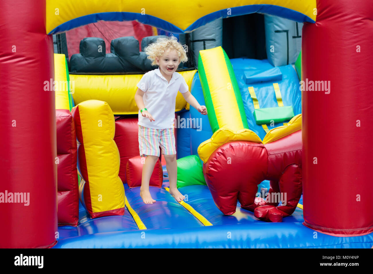 Kind springen auf bunten Spielplatz Trampolin. Kinder springen in Aufblasbare bounce Burg auf Kindergarten Geburtstag Aktivität und spielen Mitte für Sie Stockfoto