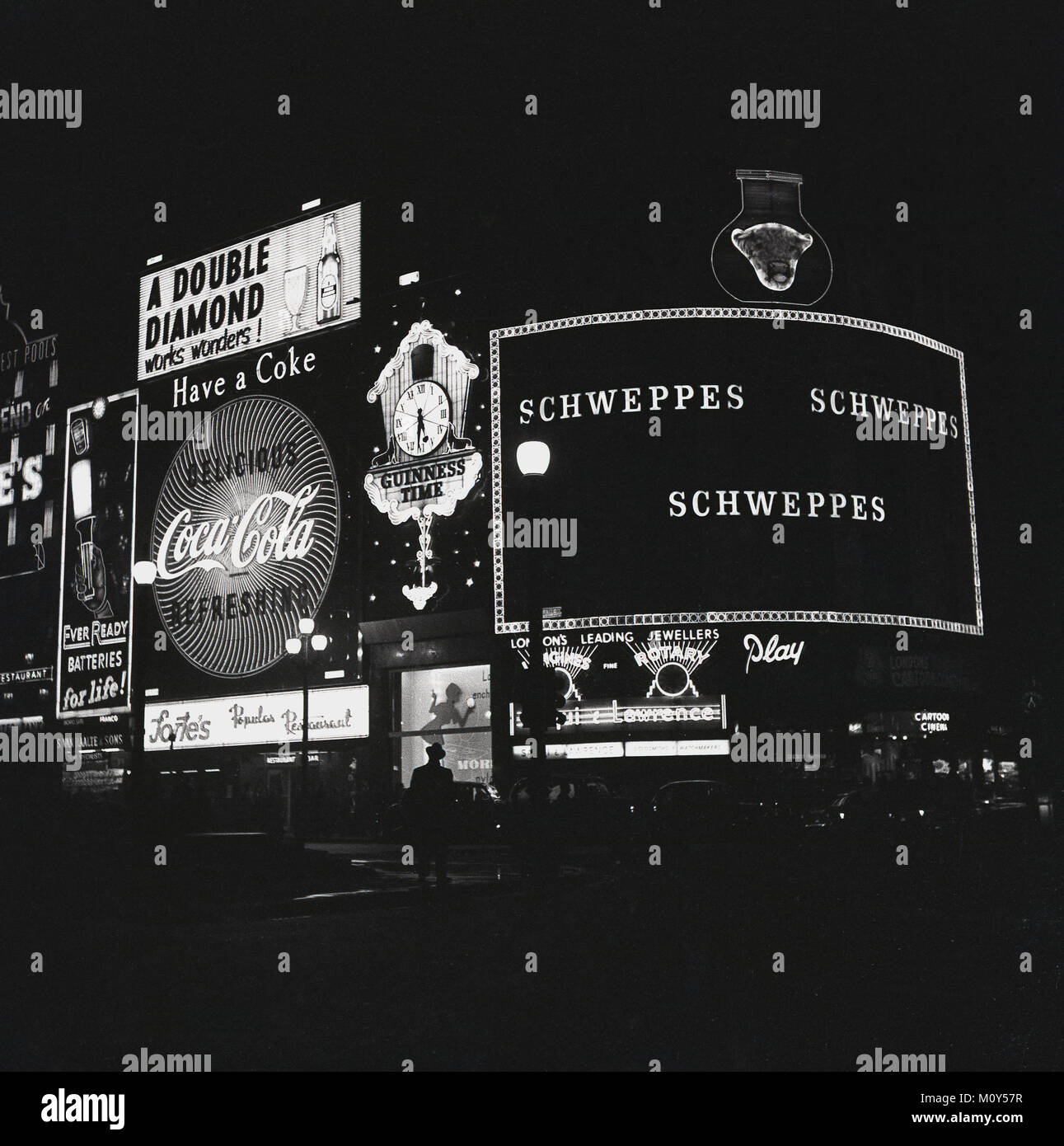 1960, historische Abbildung, die den berühmten Neonreklamen und Slogans, die Beleuchtung der Nacht am Piccadilly Circus Kreisverkehr im West End von London, England, UK. Stockfoto