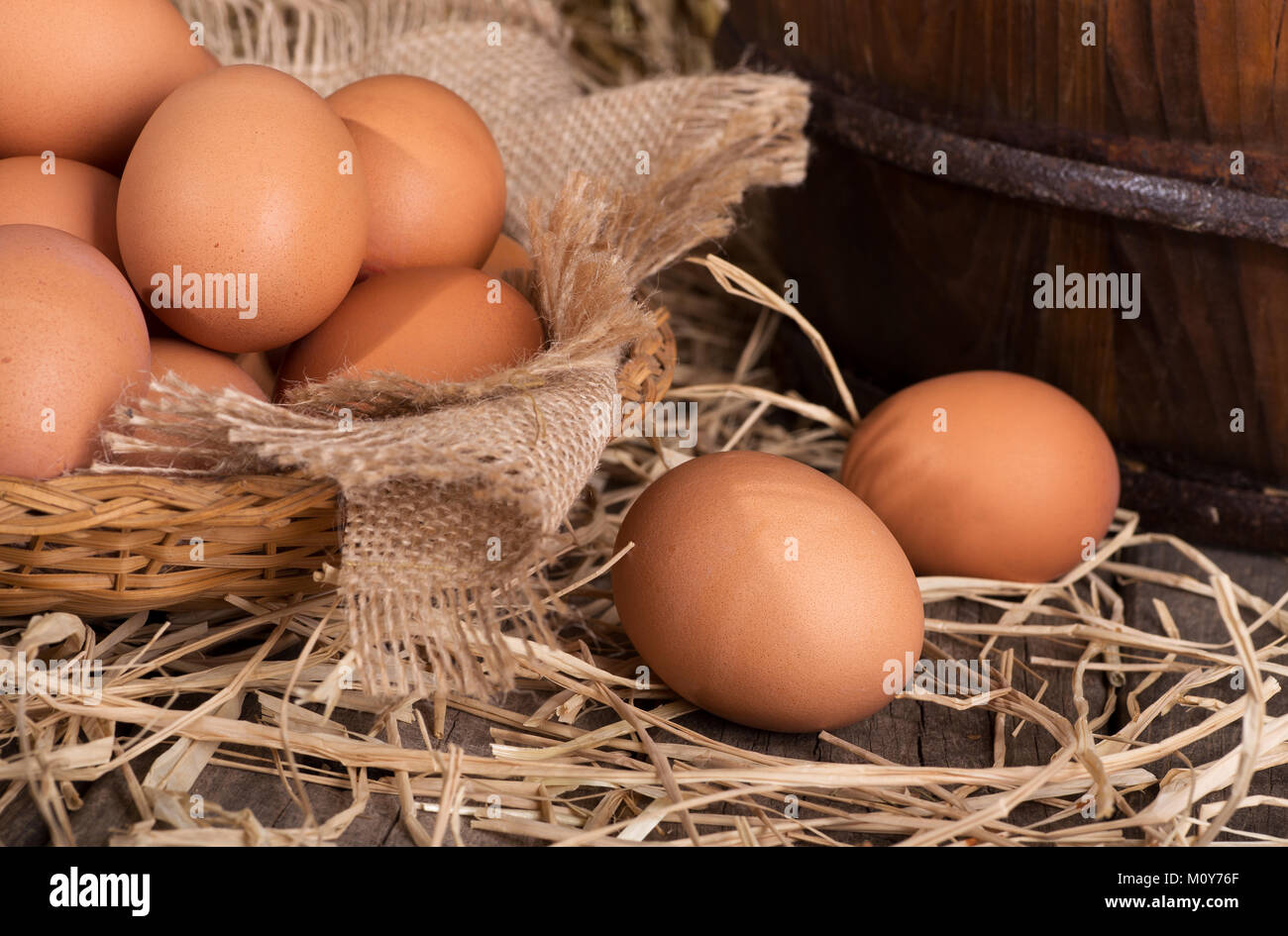 Braun Huhn Eier in einen Korb und auf einem Stroh gedeckt Holz- Oberfläche Stockfoto