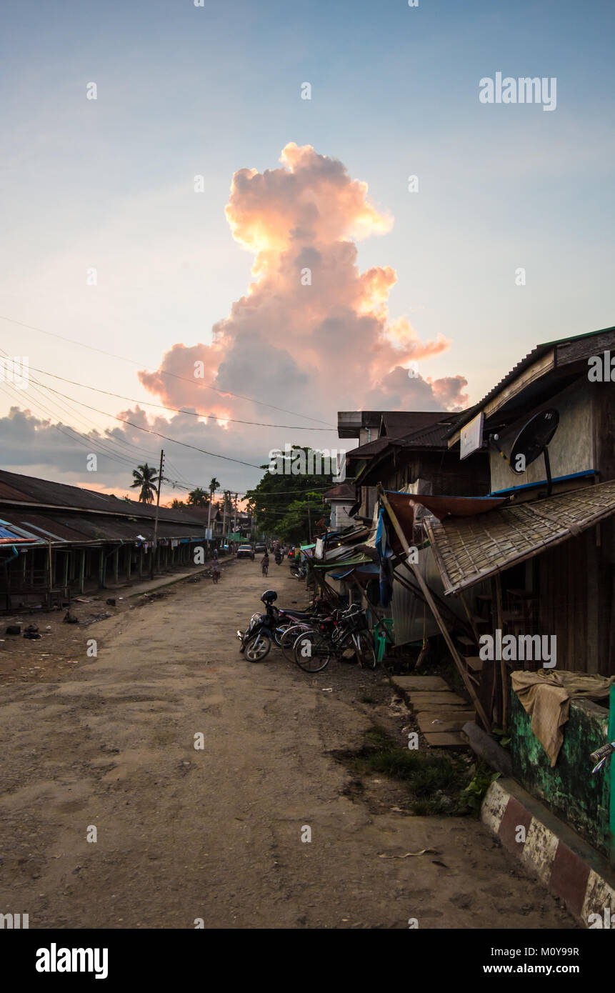 Eine normale, sandige Straße mit shack Gebäude, die durch einen riesigen Monsun Cloud in Mrauk U, Rakhine, Myanmar überschattet Stockfoto