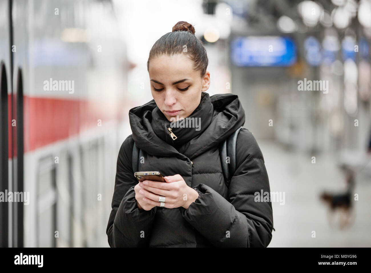 Junge Frau auf einer Plattform im Hauptbahnhof sieht auf Ihrem Smartphone, Köln, Nordrhein-Westfalen, Deutschland Stockfoto