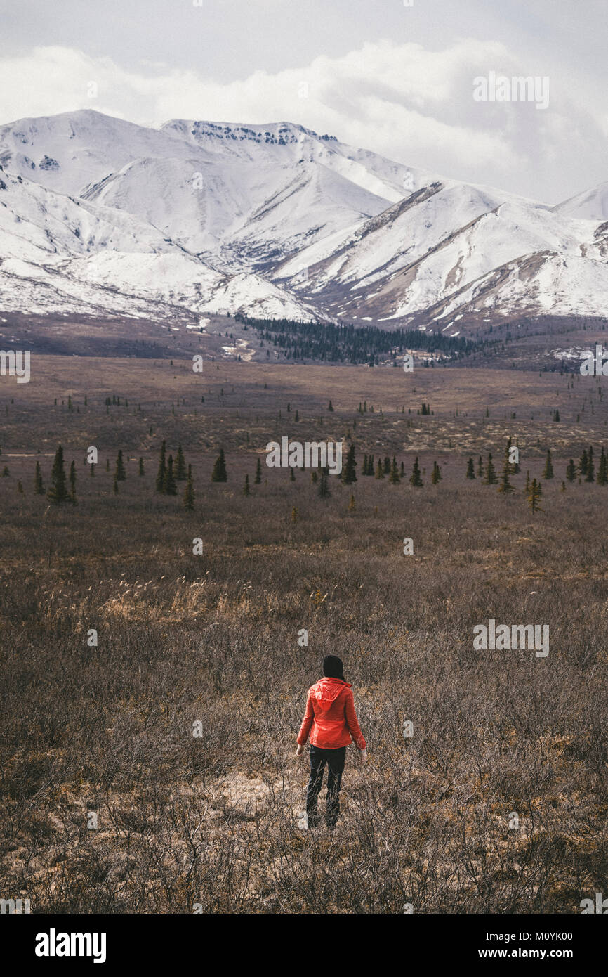 Kaukasische Frau, die im Feld in der Nähe von verschneiten Berg Stockfoto