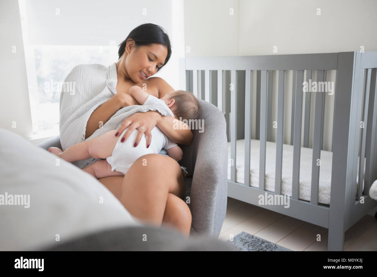 Frau sitzt in einem Sessel Stillen baby Sohn Stockfoto