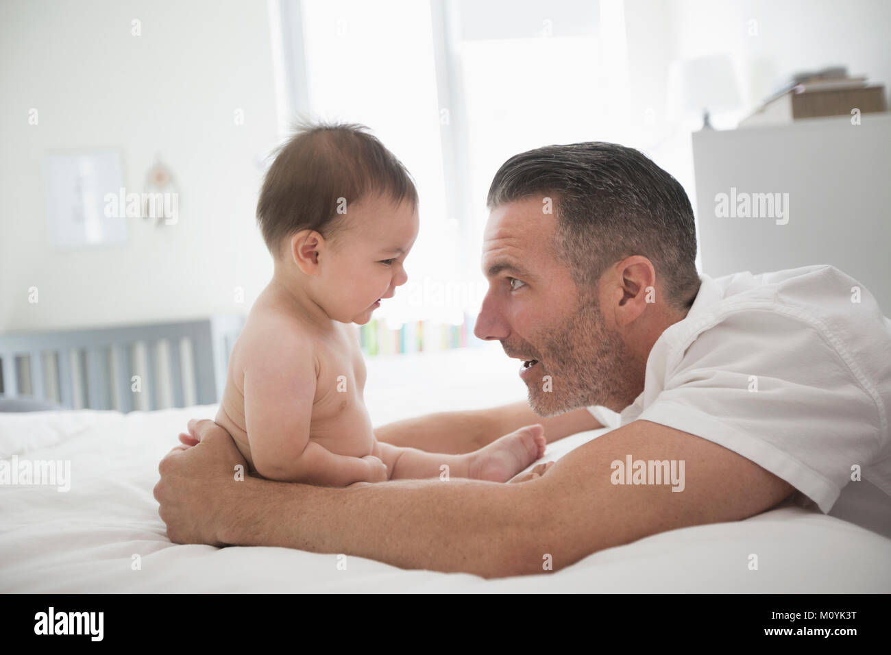 Vater spielen mit Baby Sohn sitzen auf dem Bett Stockfoto