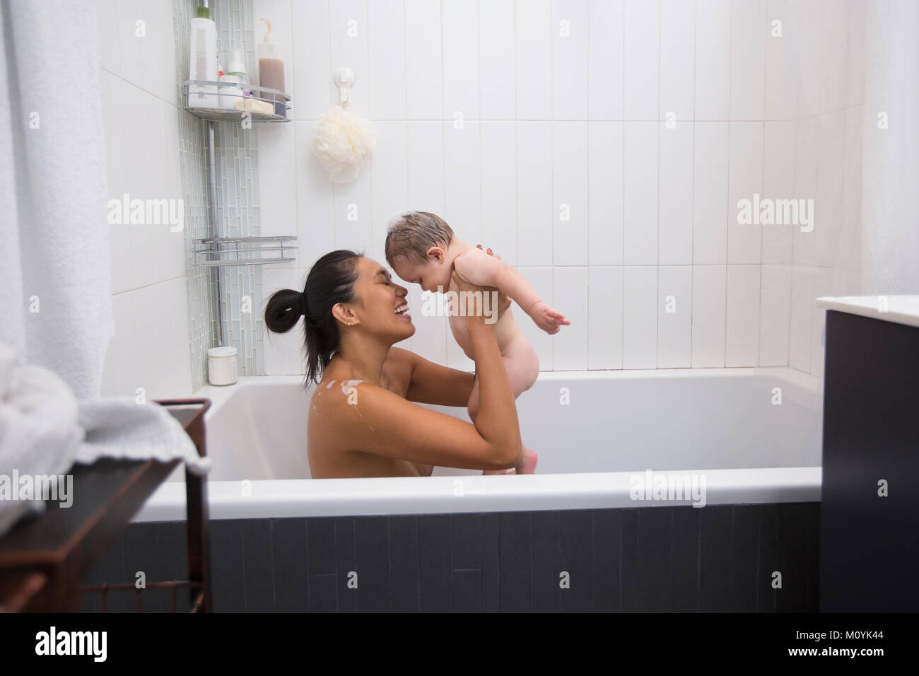 Die Mutter sitzt in der Badewanne Holding baby Sohn Stockfoto