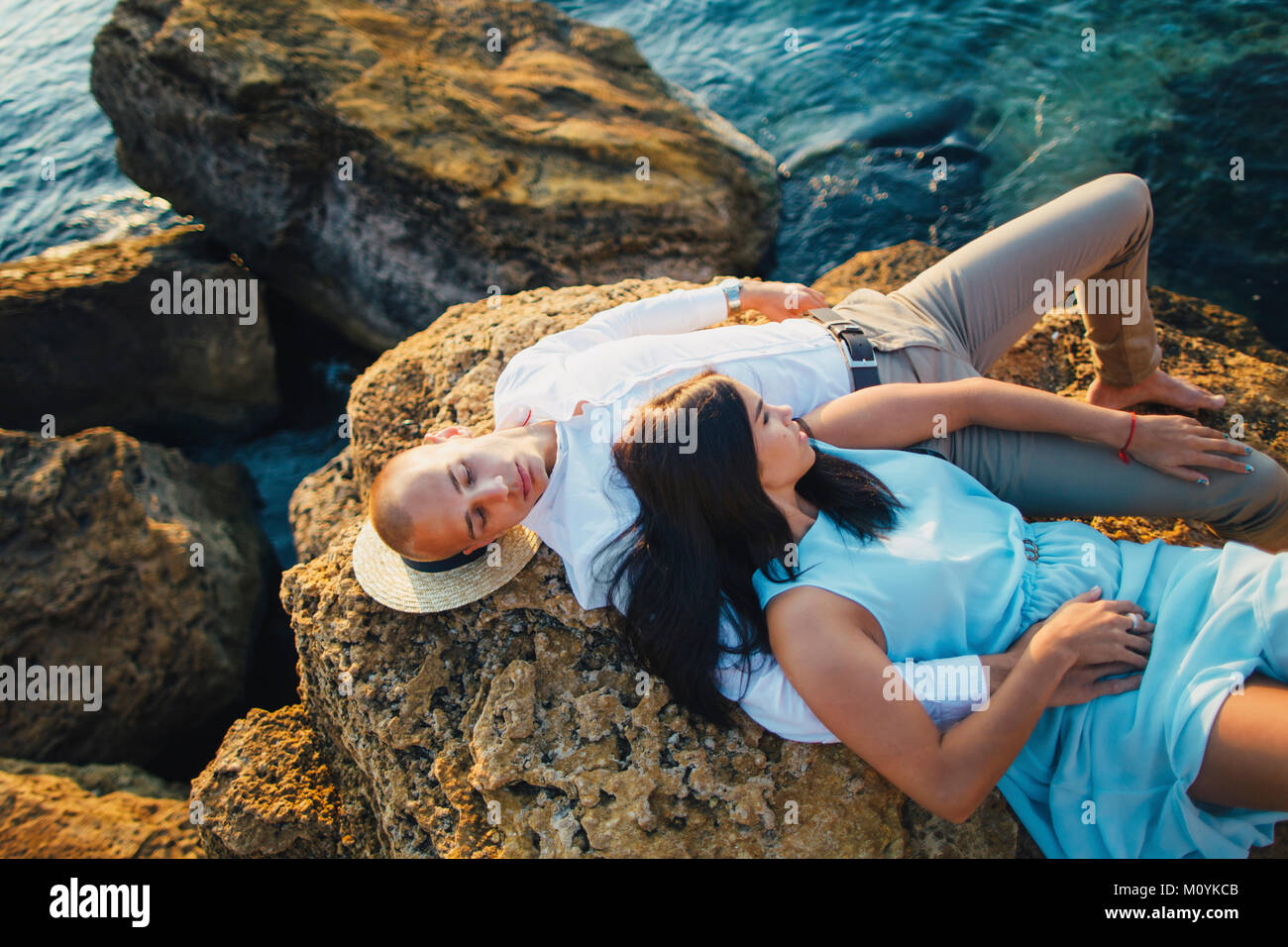 Kaukasische paar Festlegung auf den Felsen am Strand Stockfoto