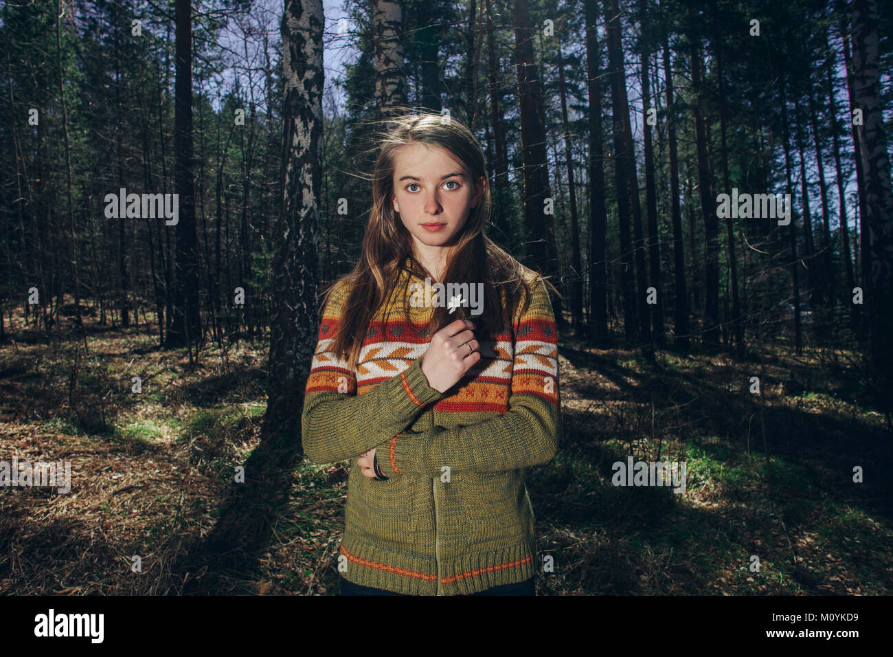 Ernsthafte kaukasische Frau mit Blume im Wald Stockfoto