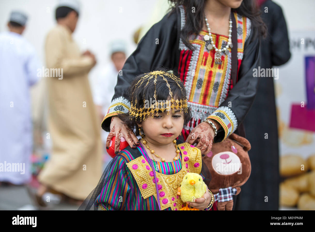 Nizwa, Oman - 26. Juni 2017: kleines Mädchen in traditionellen Outfit, mit ihrer Mutter zu einem Spielzeug Markt an einem Tag des Eid al Fitr Stockfoto