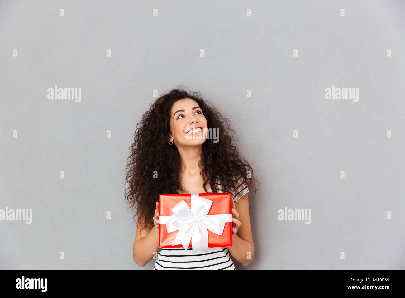 Smiling pretty woman holding Geschenk verpackt, Gefühl Freude an Silvester zu erhalten Stockfoto