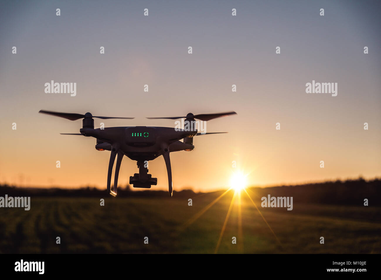 Foto von einem fliegenden weißen Professionelle quadcopter drone Kamera bei Sonnenuntergang Stockfoto