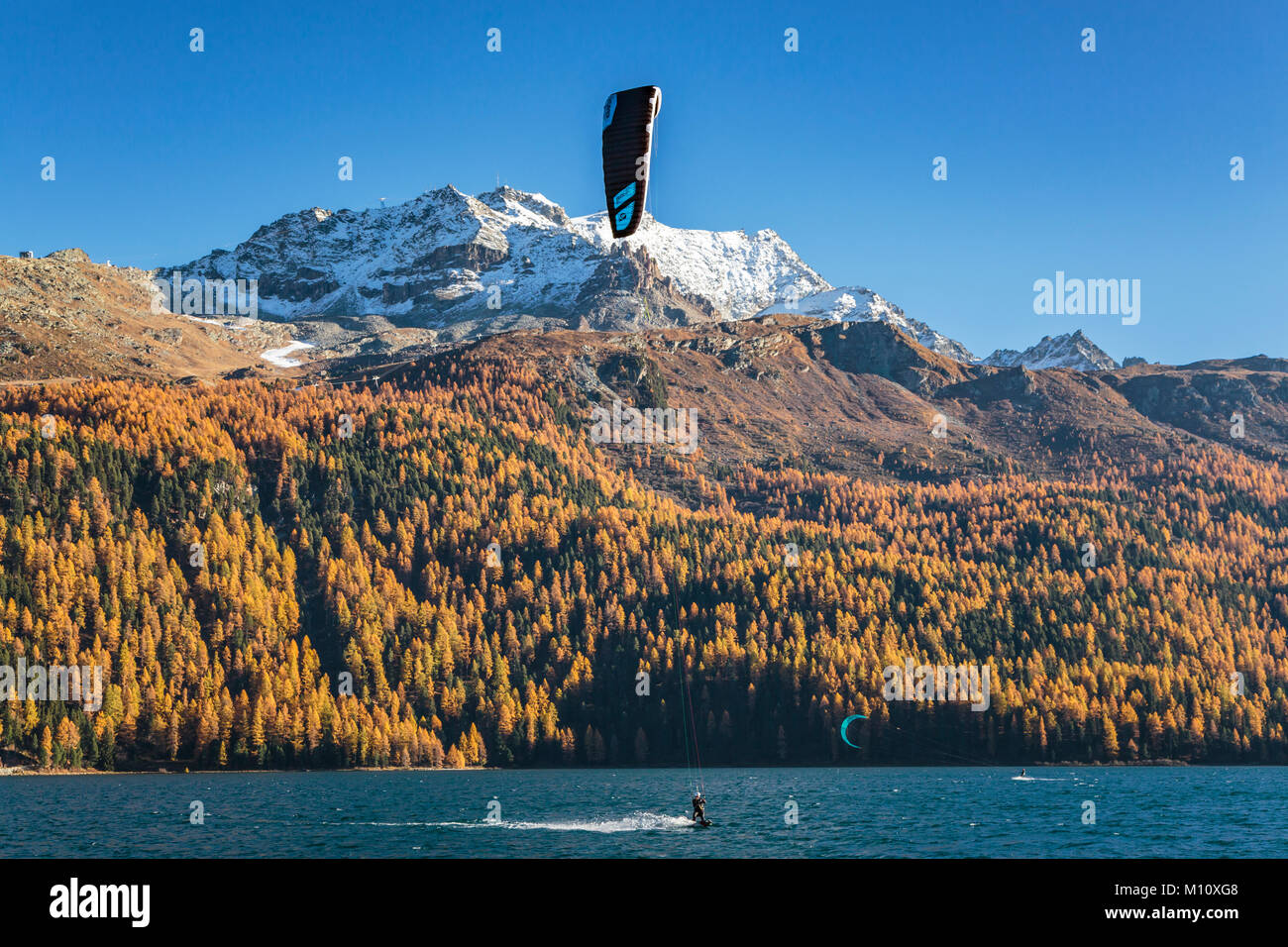 Windsurfen am Lake Silvaplana mit Herbstfarben Farbe in der Lärchen im Engadin, Graubuden, Schweiz, Europa. Stockfoto