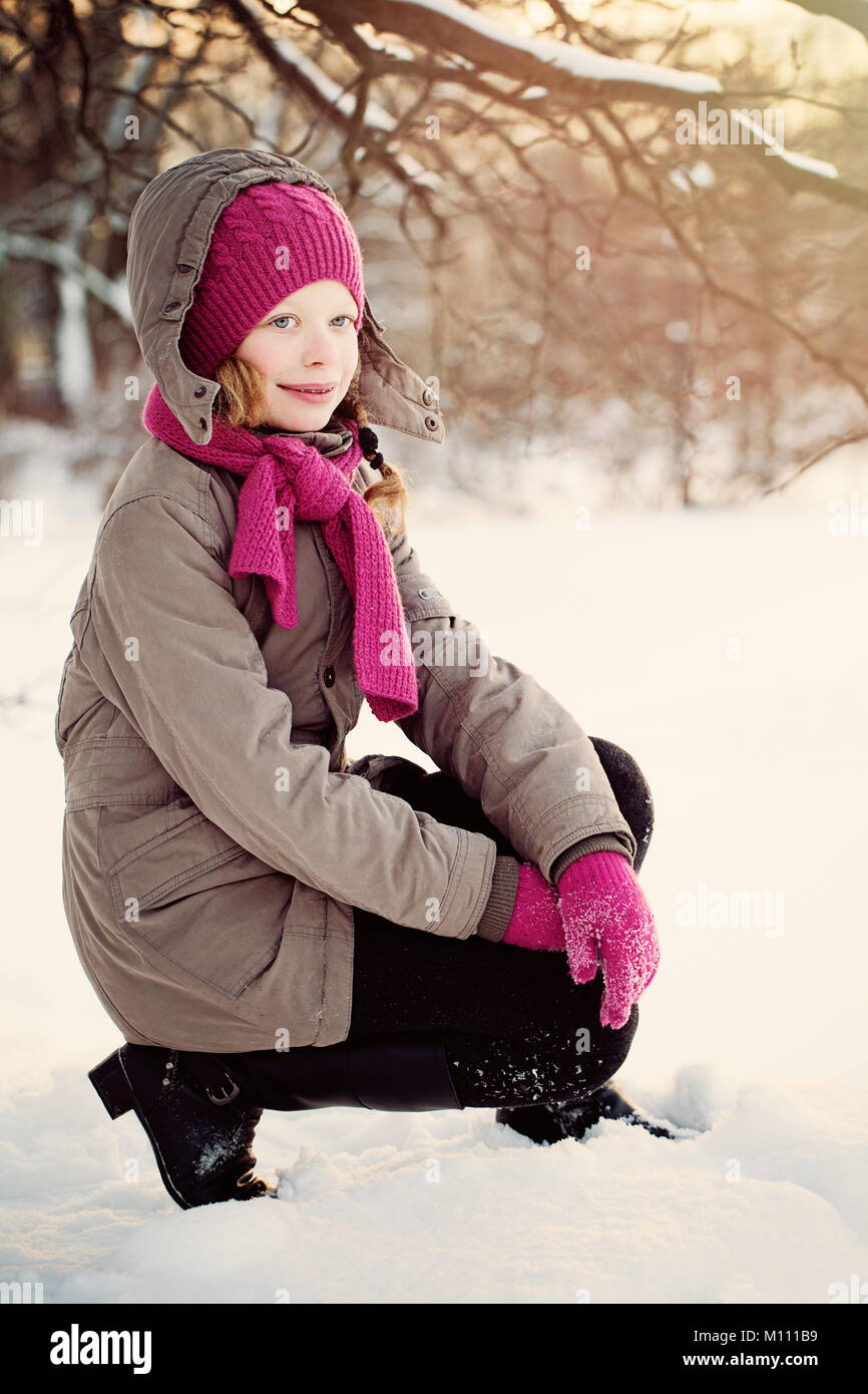 Glückliches Kind Mädchen im Winter Jacke und rosa Wollmütze und Schal in Winter Park im Freien Stockfoto
