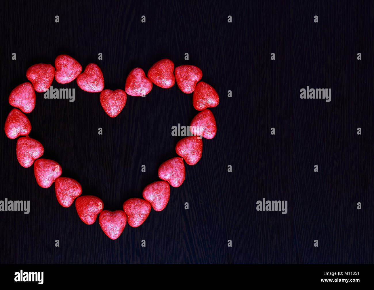 Rotes Herz aus kleinen Herzen auf dunklem Hintergrund, Nahaufnahme, Konzept der Valentinstag Stockfoto