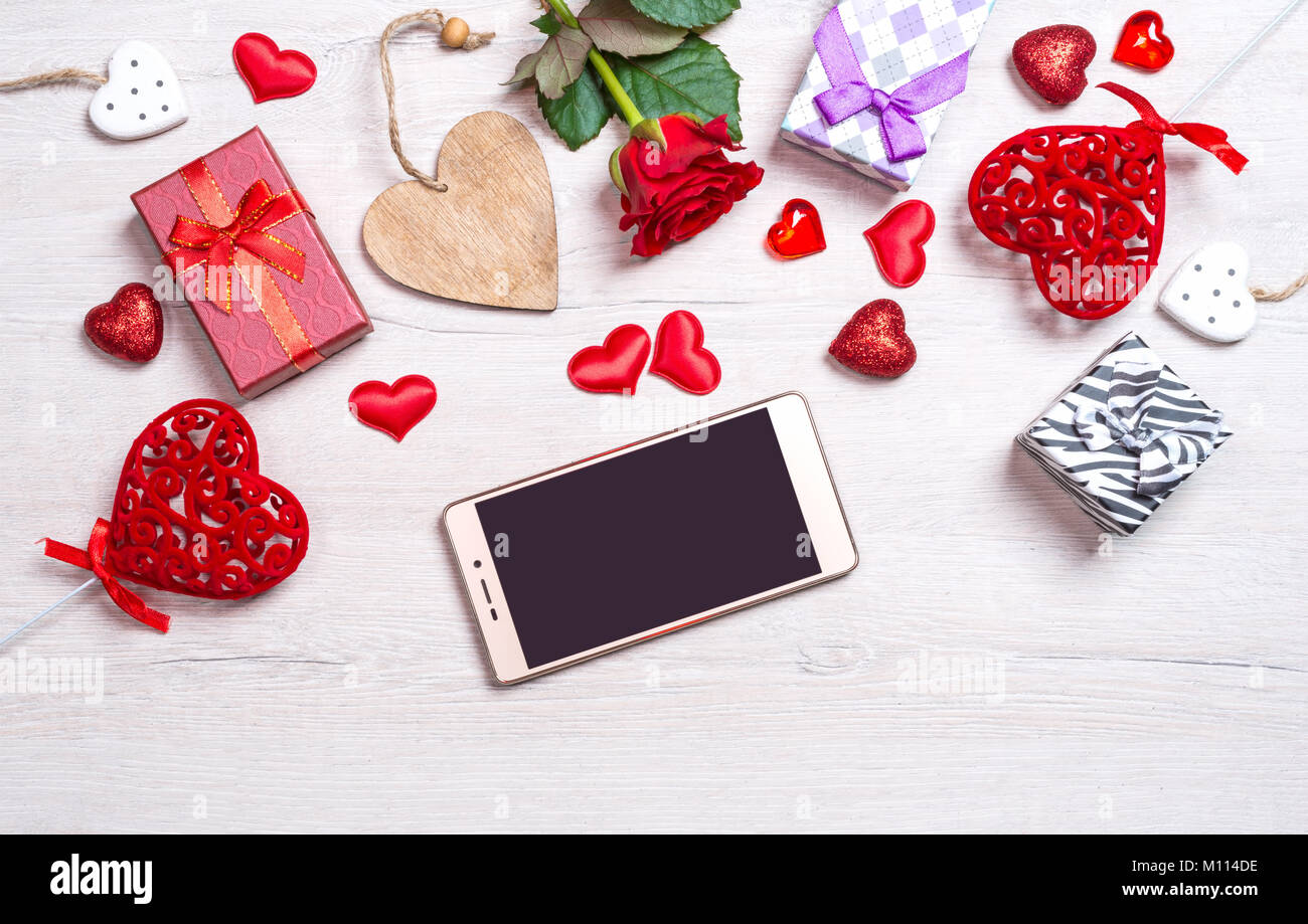 Holz- weißen Hintergrund mit Herzen, Geschenke, rote Rose und Smartphone. Das Konzept der Valentinstag Stockfoto