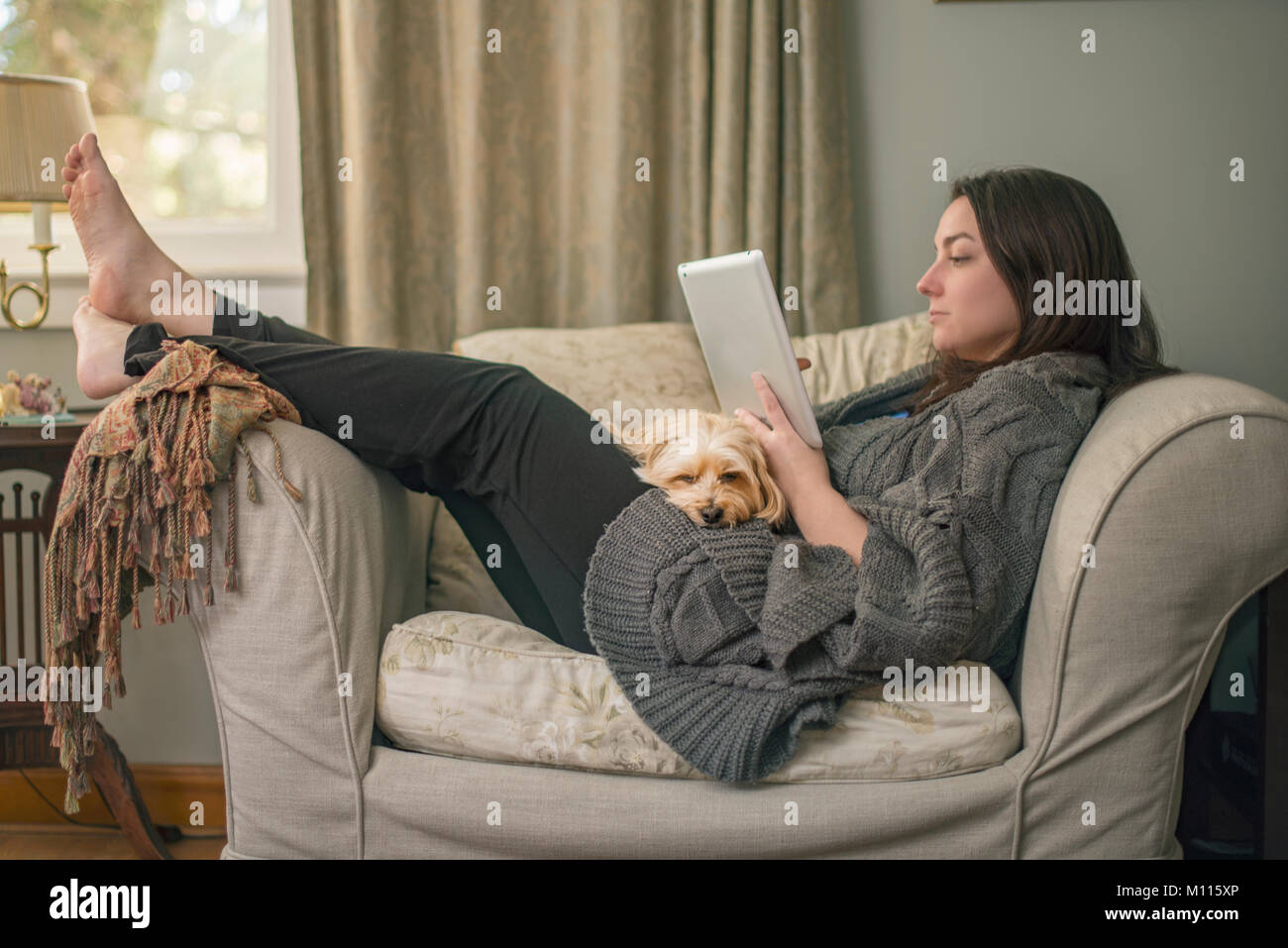 Frau Entspannung mit der Tablette und Hund Stockfoto
