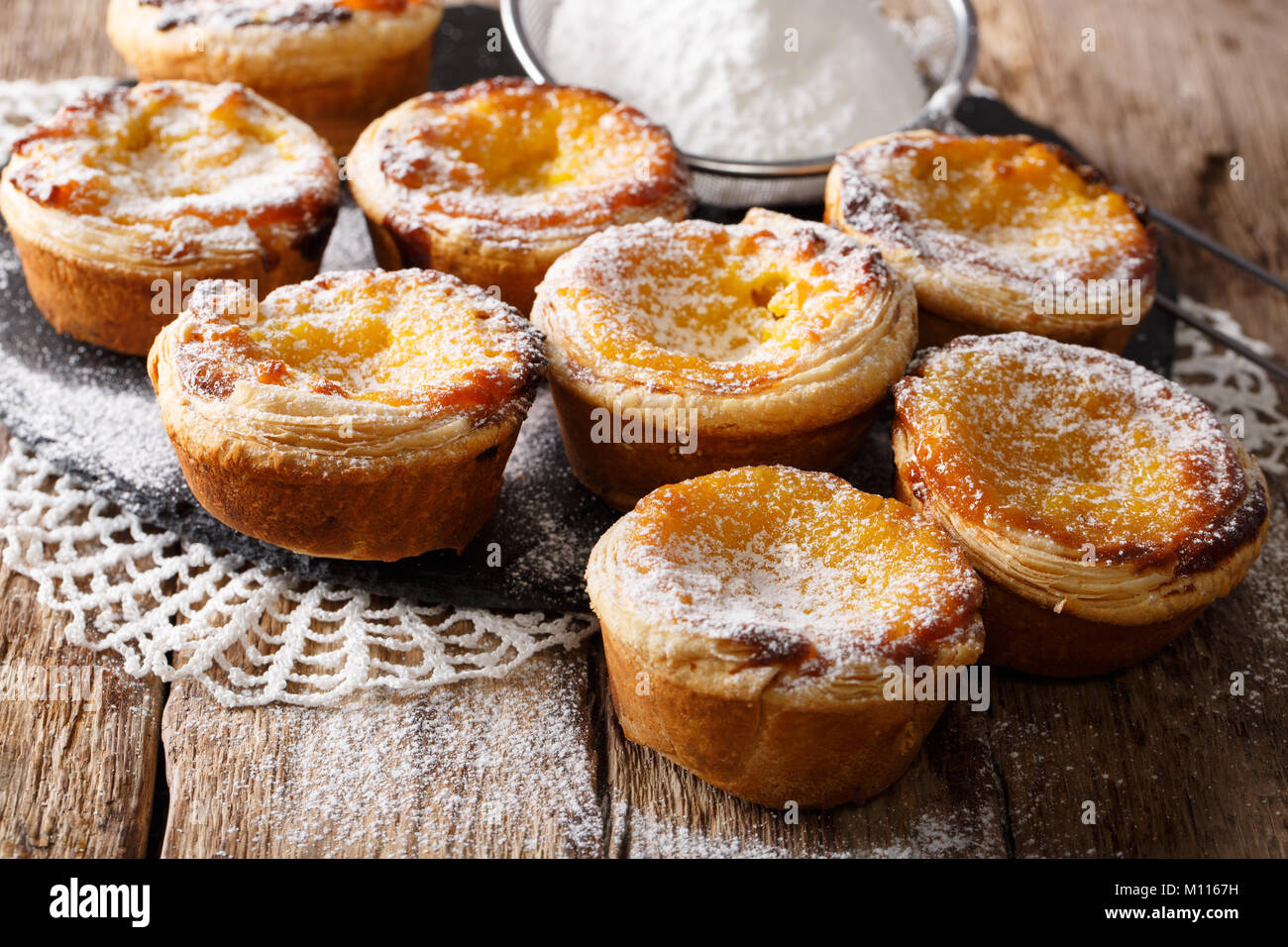 Köstliche Pastel de Nata Kuchen mit Pudding gefüllt, bestreut mit Puderzucker close-up auf dem Tisch. Horizontale Stockfoto