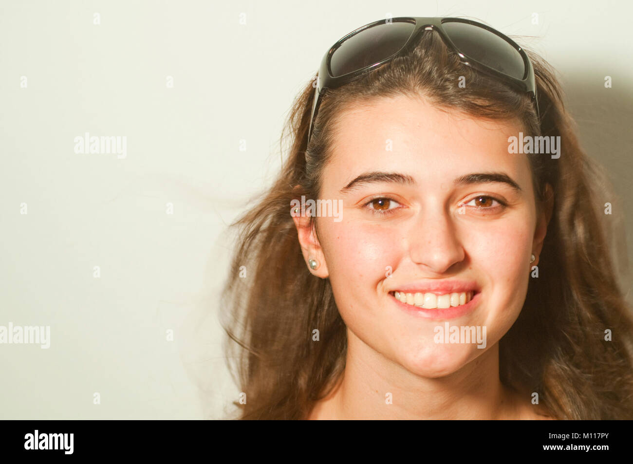 Junge Frau eine Sonnenbrille trug, lächelnd und mit Blick auf die Kamera. Stockfoto