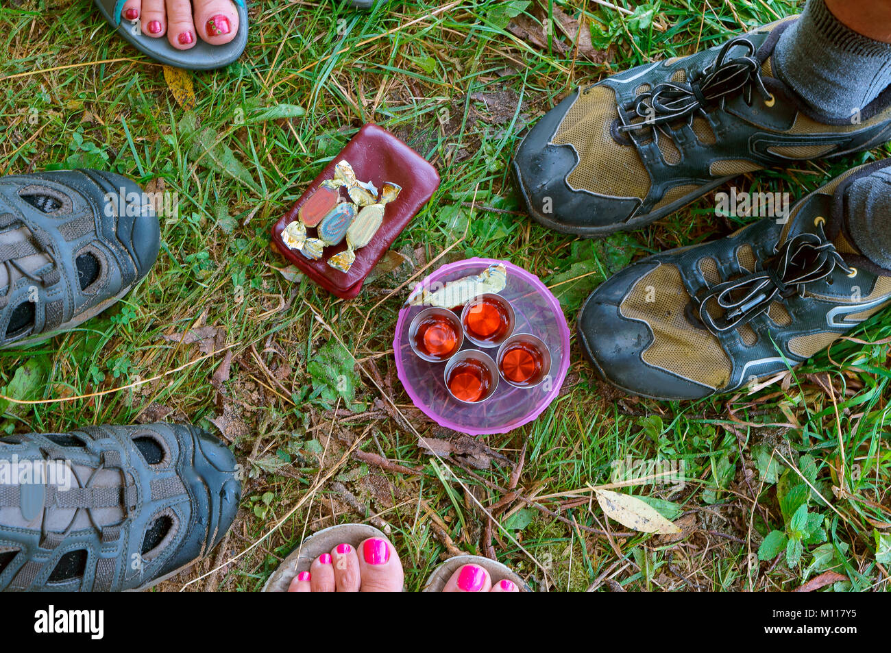 Vier Gläser, vier Beinpaare, vier Bonbons, ein Picknick Stockfoto