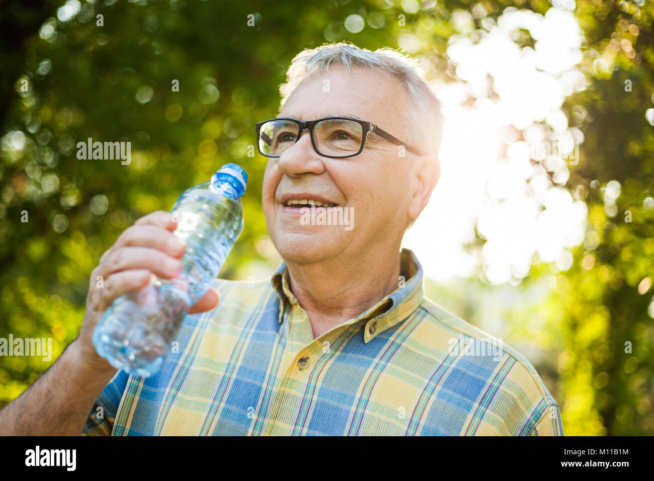 Gerne älterer Mann ist Trinkwasser in den Park. Stockfoto
