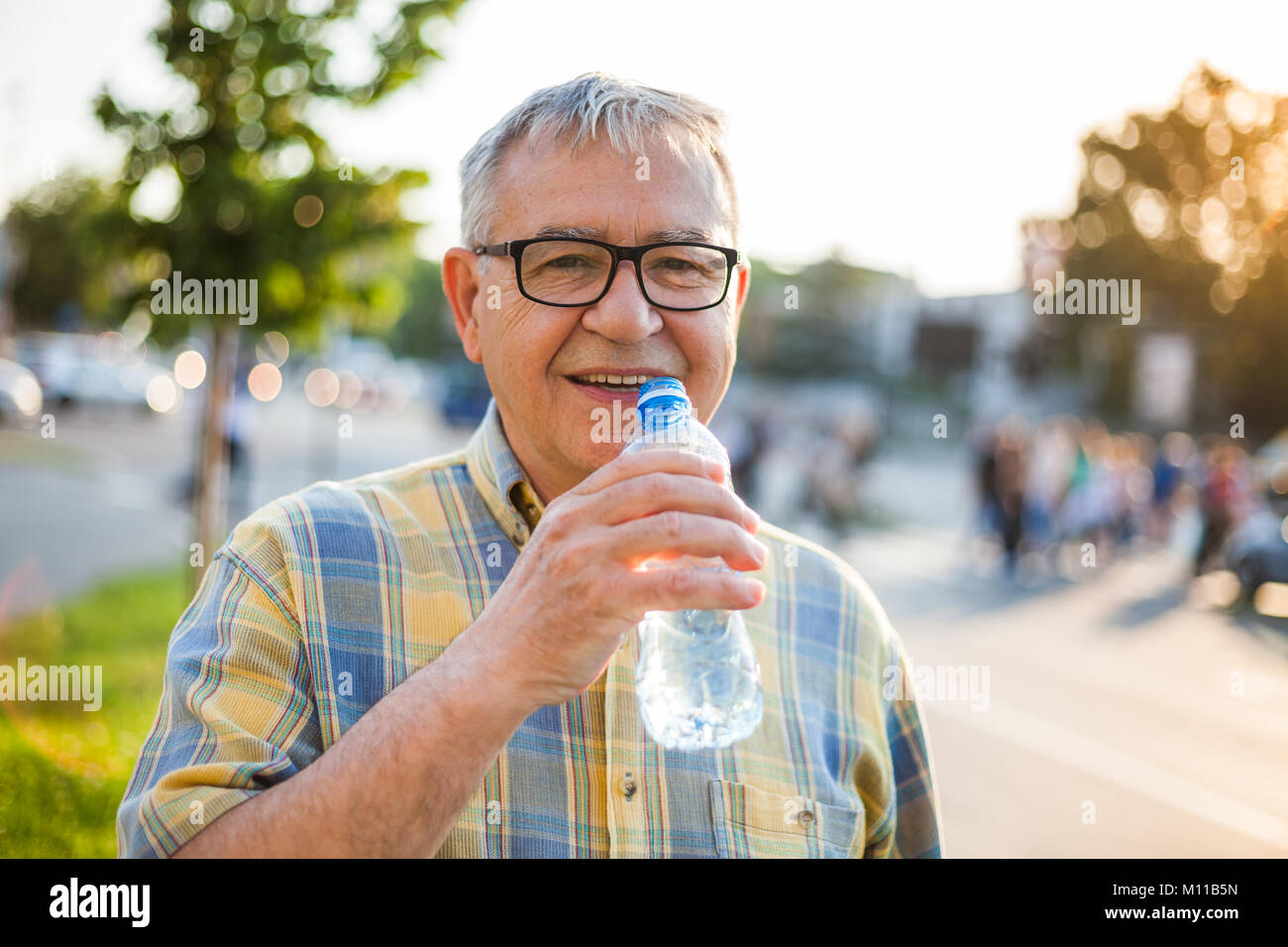 Gerne älterer Mann ist Trinkwasser in der Stadt. Stockfoto