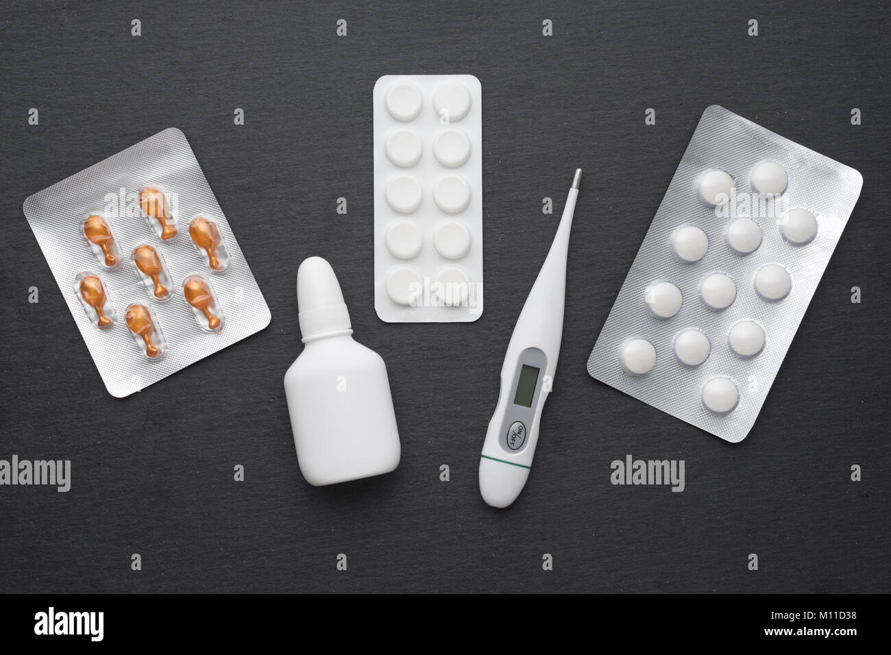 Thermometer, nasale Tropfen und Tabletten auf dunklem Schiefer. Flach. Medikamente für die Behandlung, Health Care Konzept Stockfoto