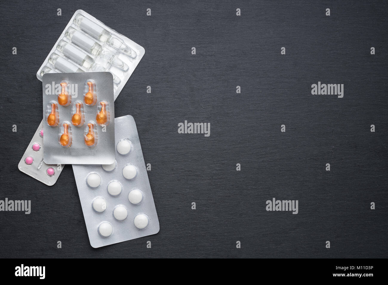 Verschiedene Tabletten, Kapseln und Ampullen auf Schiefer. Medikamente für die Behandlung, Health Care Konzept Stockfoto