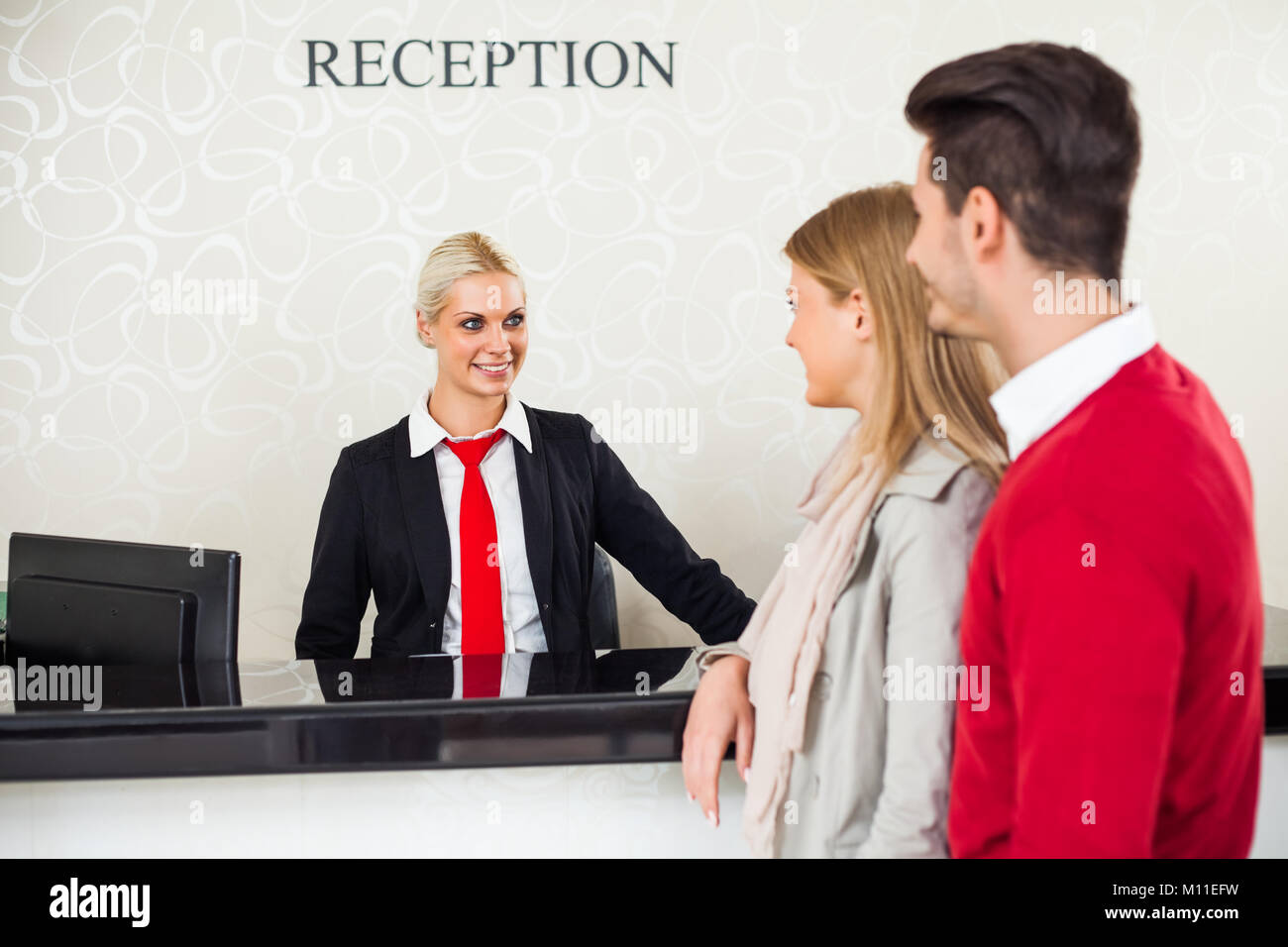 Junges Paar Check-in im Hotel Rezeption Stockfoto