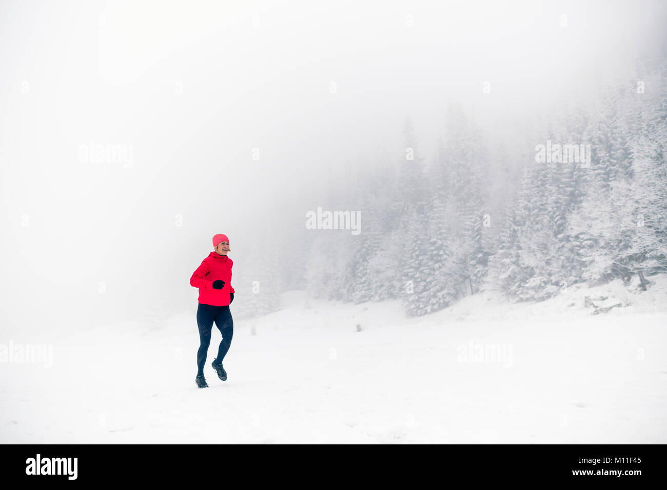 Winter läuft Frau auf Schnee im Weißen Berge und Wald. Sport, Fitness Inspiration und Motivation. Junge glücklich Athlet, auf Schnee, w Stockfoto