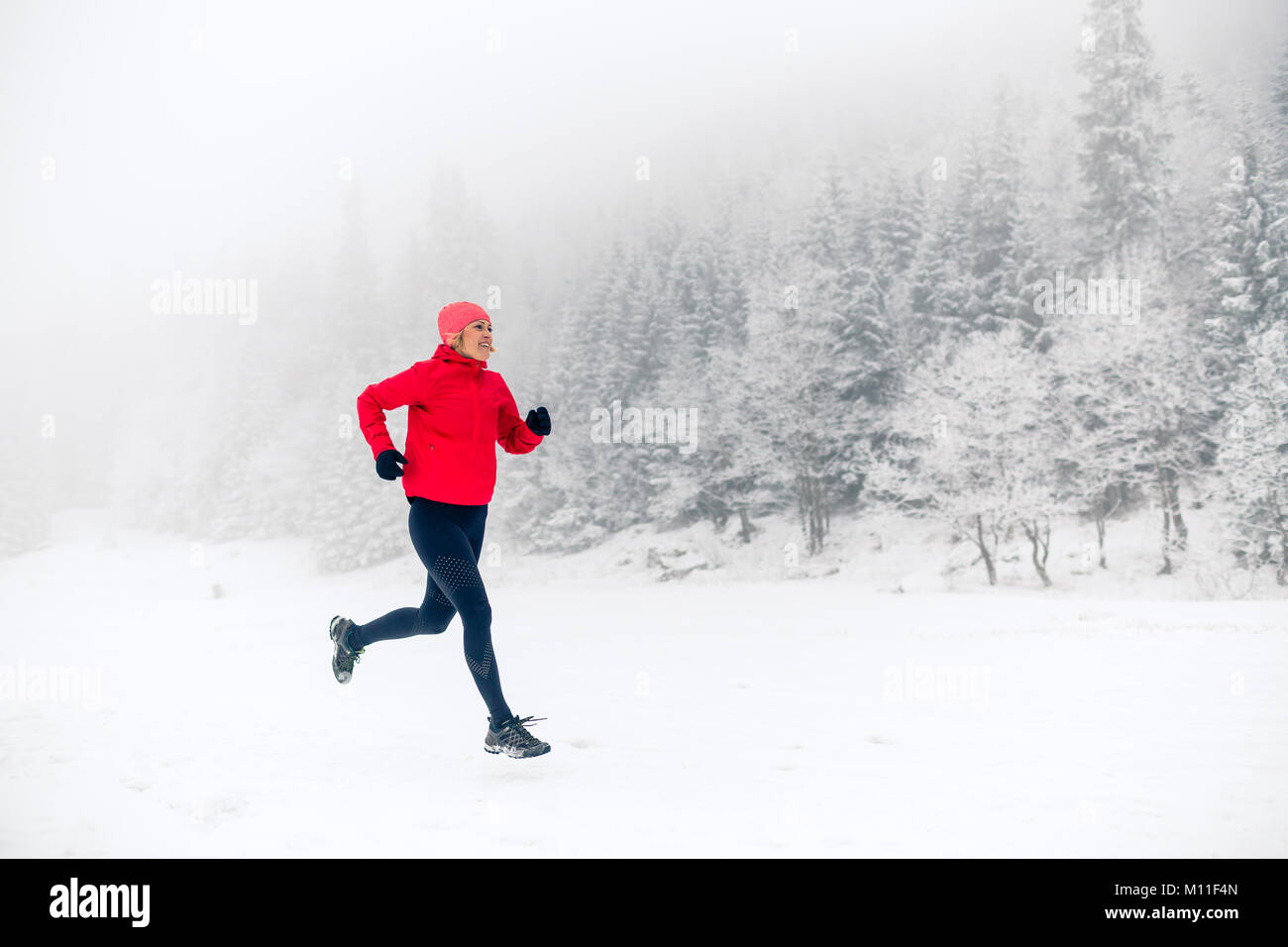 Frau Trail Running auf Schnee im Winter Berge und Wald. Sport, Fitness Inspiration und Motivation. Junge glücklich Athlet, auf Schnee, w Stockfoto