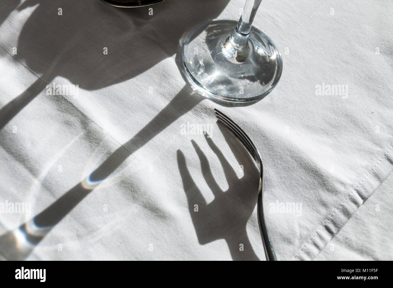Gabel und Weinglas Schatten abstrakt Design auf der weißen Tischdecke Stockfoto