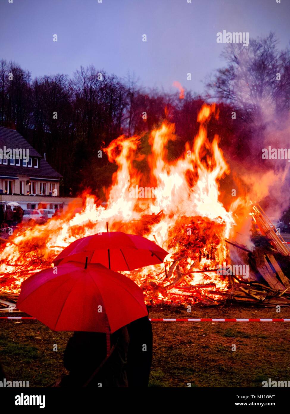Rote Schirme vor einem Lagerfeuer am Ostersonntag Abends Stockfoto