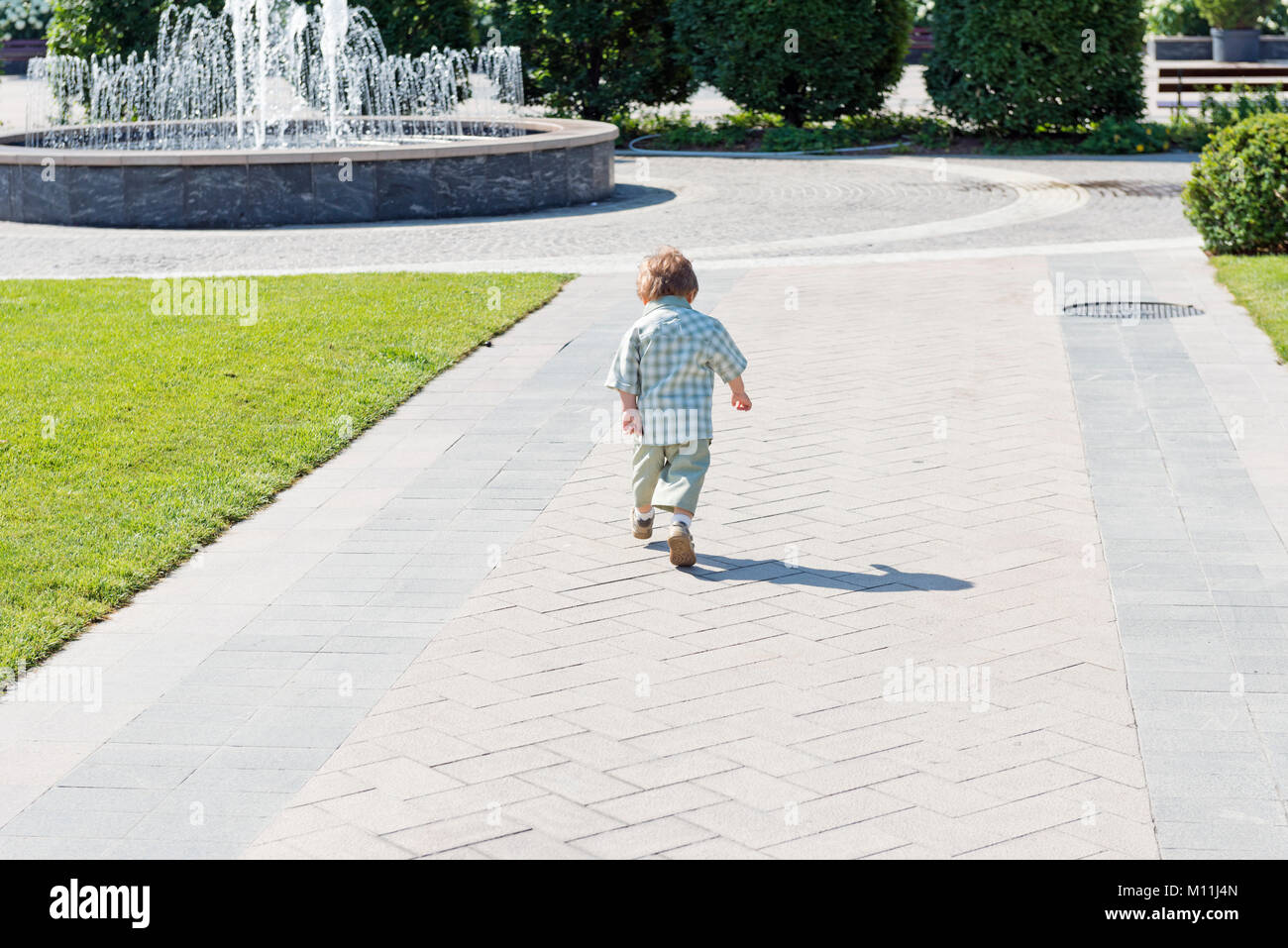 Drei Jahre altes Kind im Park mit Springbrunnen und blauer Himmel Stockfoto