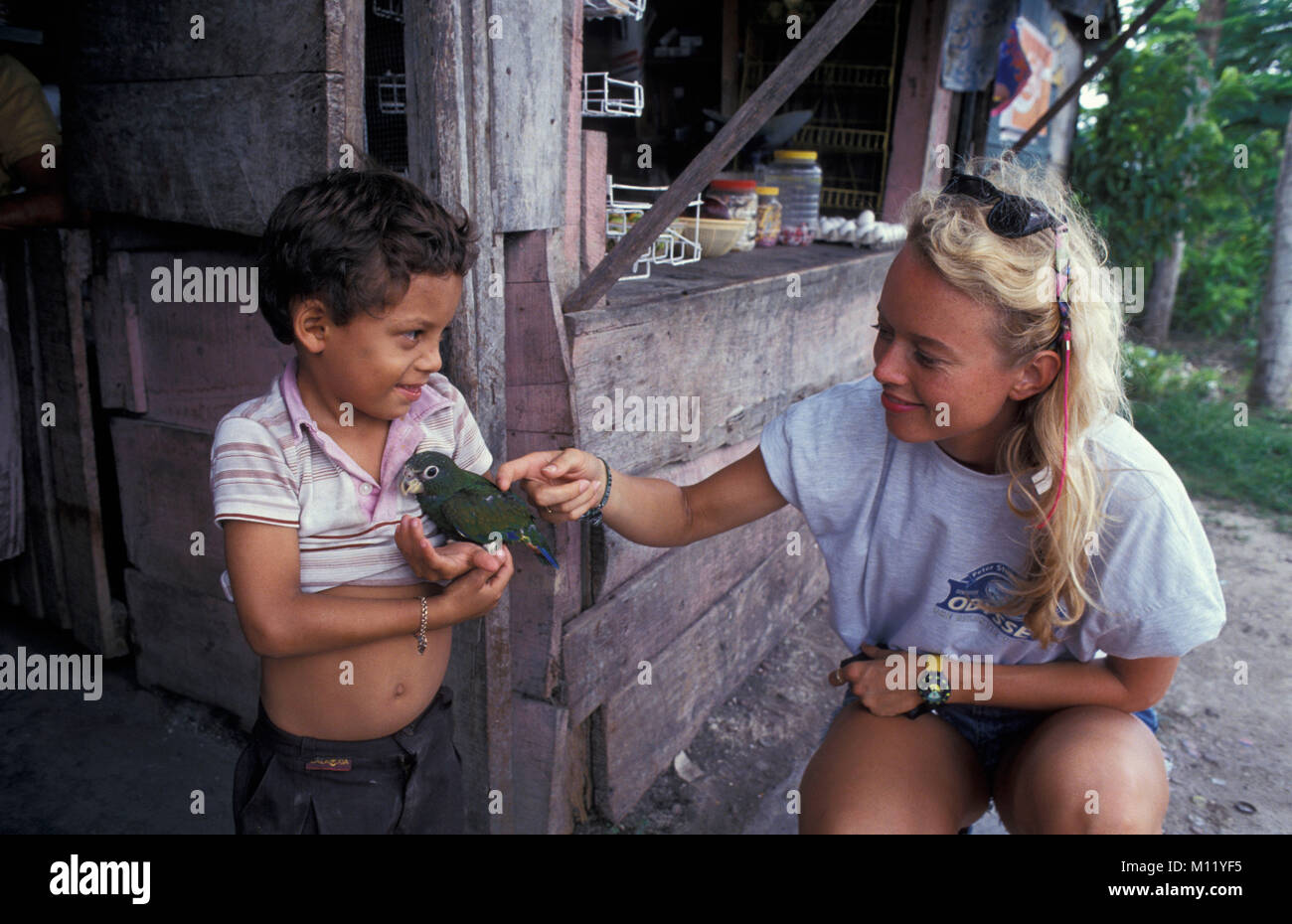 Mexiko. Chetumal. Weibliche Touristen streicheln Papagei von Jungen gehalten, lächelnd. Stockfoto