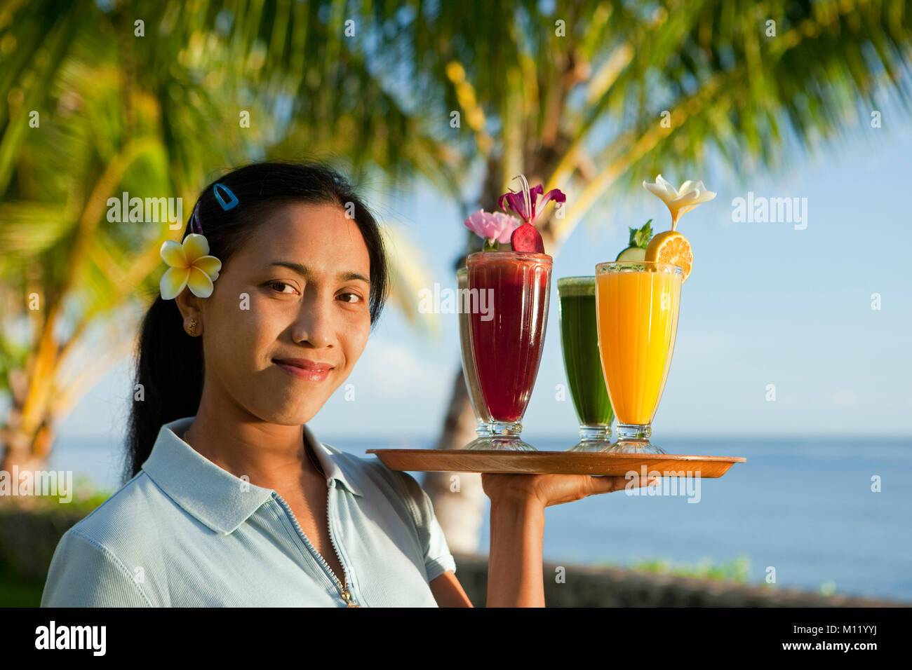 Indonesien, Insel Bali, in der Nähe von tejakula Dorf, Gaia Oasis Resort. Kellnerin mit Fruchtcocktails. Stockfoto
