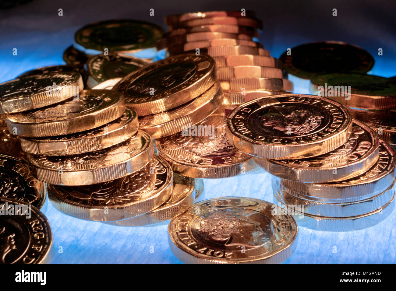 Neue UK ein Pfund Münzen, Lose arrangiert, und oben leuchtet auf einen blau beleuchteten Hintergrund. Stockfoto
