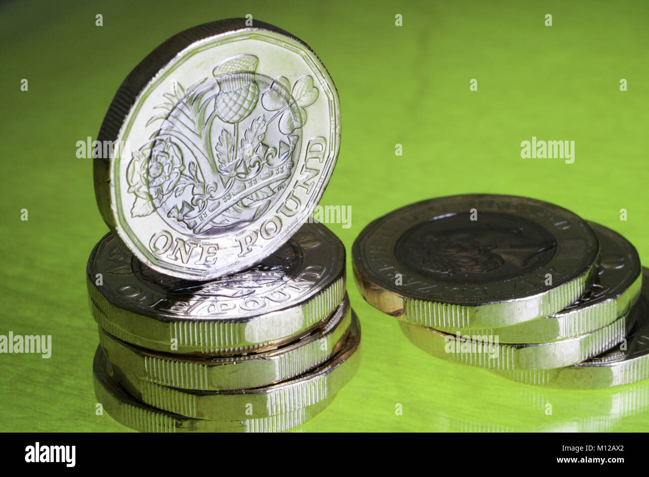 Neue Pfund Münzen auf einem grün leuchtenden Base mit einer hervorgehobenen Münze senkrecht angeordnet Stockfoto