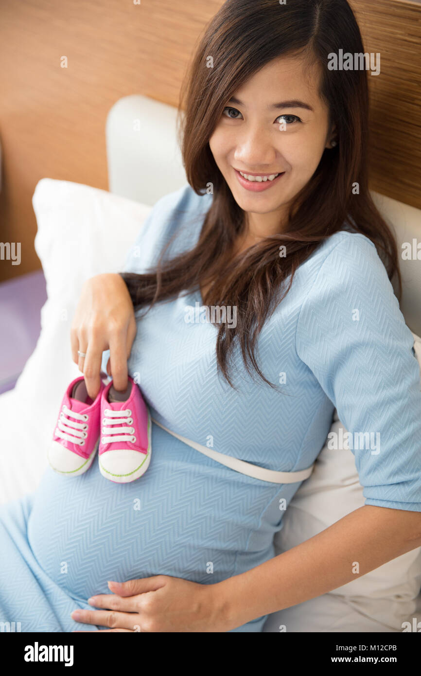 Ein Porträt eines asiatischen schwangere Frau Holding Baby Schuhe in den Händen. Stockfoto