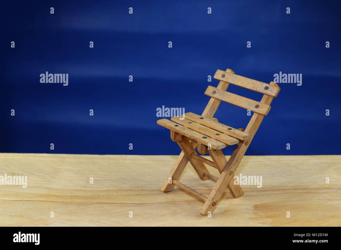 Eine Holzterrasse Stuhl als Symbol für Urlaub und Entspannung auf einem blauen Hintergrund Stockfoto