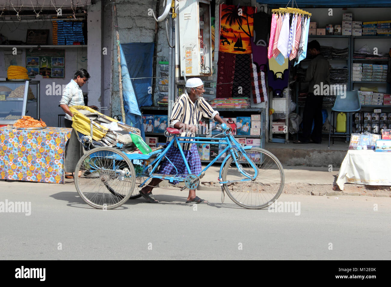 Mann drücken Zyklus Rikscha entlang der Straße in Hyderabad, Indien Stockfoto