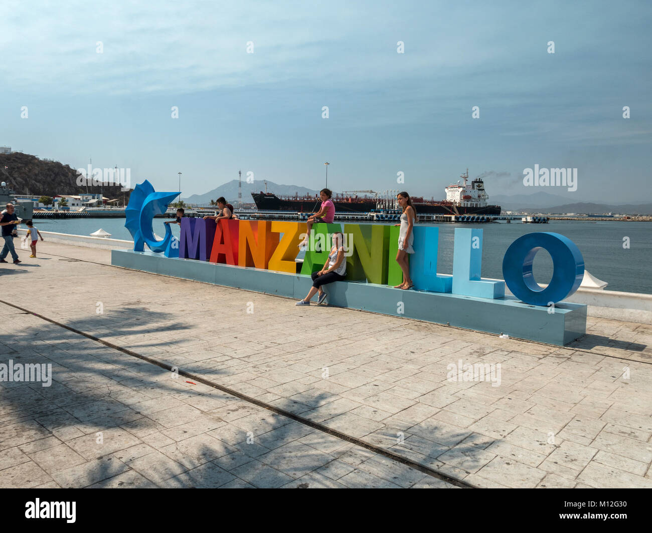 Eine Familie posieren für Fotos an der Manzanillo bunte Touristische Schild an der Waterfront von Manzanillo Colima Mexiko Stockfoto