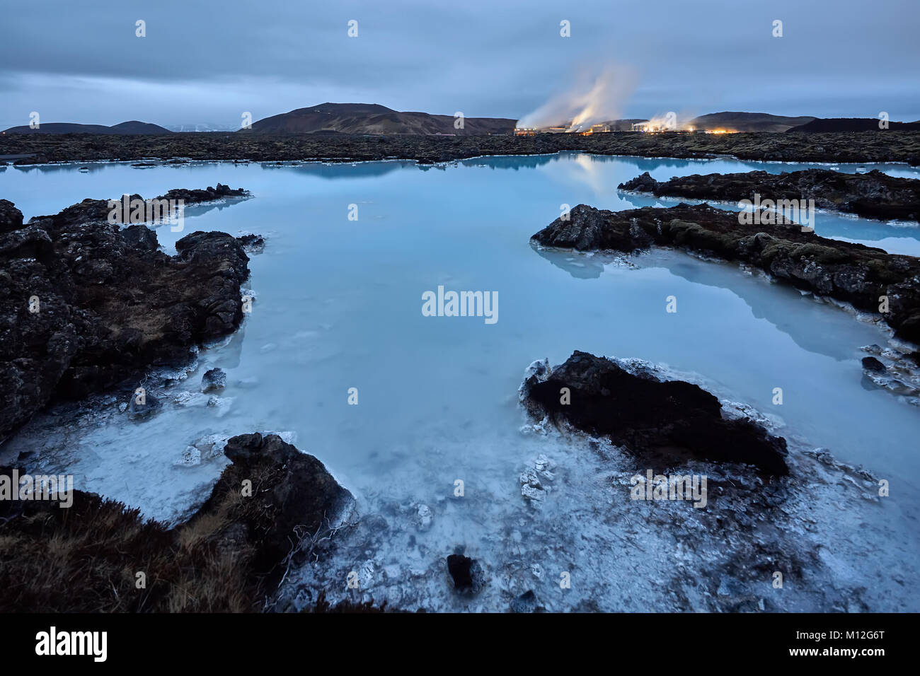 Wunderbare blaue Lagune am Abend auf dem Hintergrund der lichten Gebäuden, Bergen und dunklen Himmel in Island. Lange Belichtung Foto. Horizontale. Stockfoto