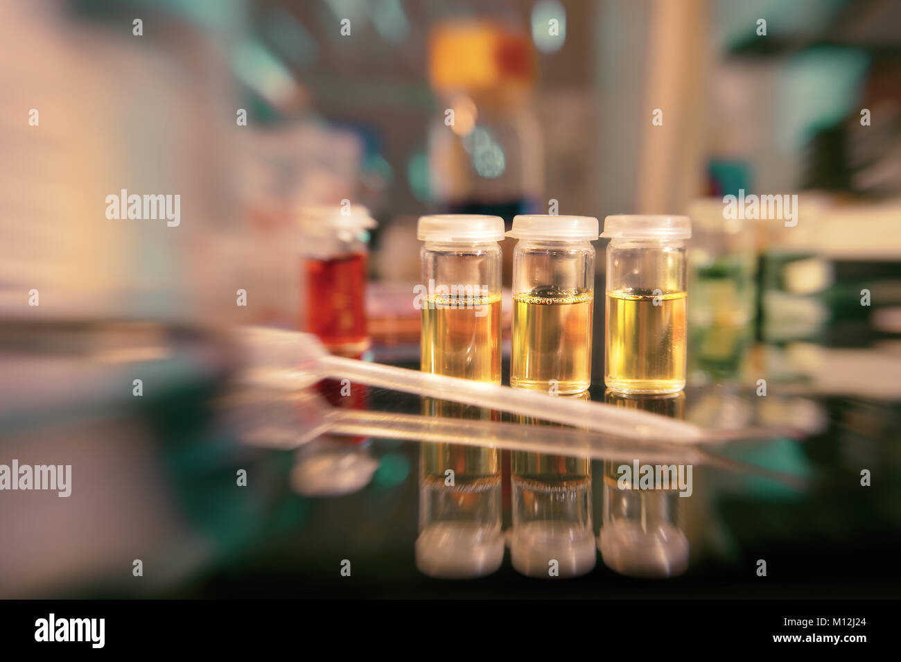 Mikrobiologie Hintergrund. Flüssige bakteriellen Kulturen auf der Bank, flachen DOF, auf der drei gelben Fläschchen Fokus Stockfoto