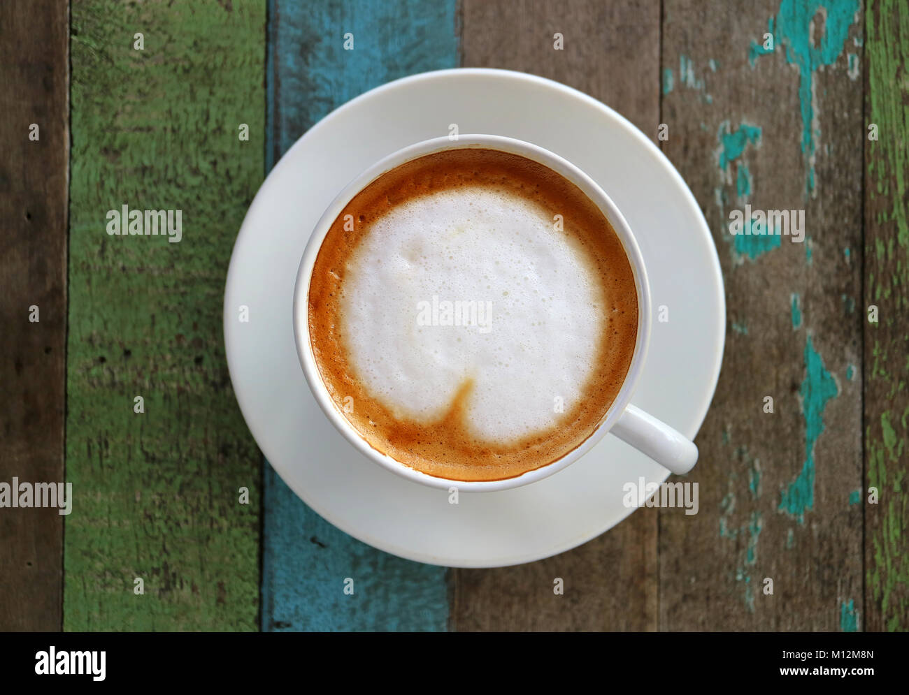 Heißer Kaffee mit Herzförmigen Latte Kunst in eine weiße Schale auf farbigen rustikalen Holztisch, Ansicht von oben mit der selektiven Fokus Stockfoto