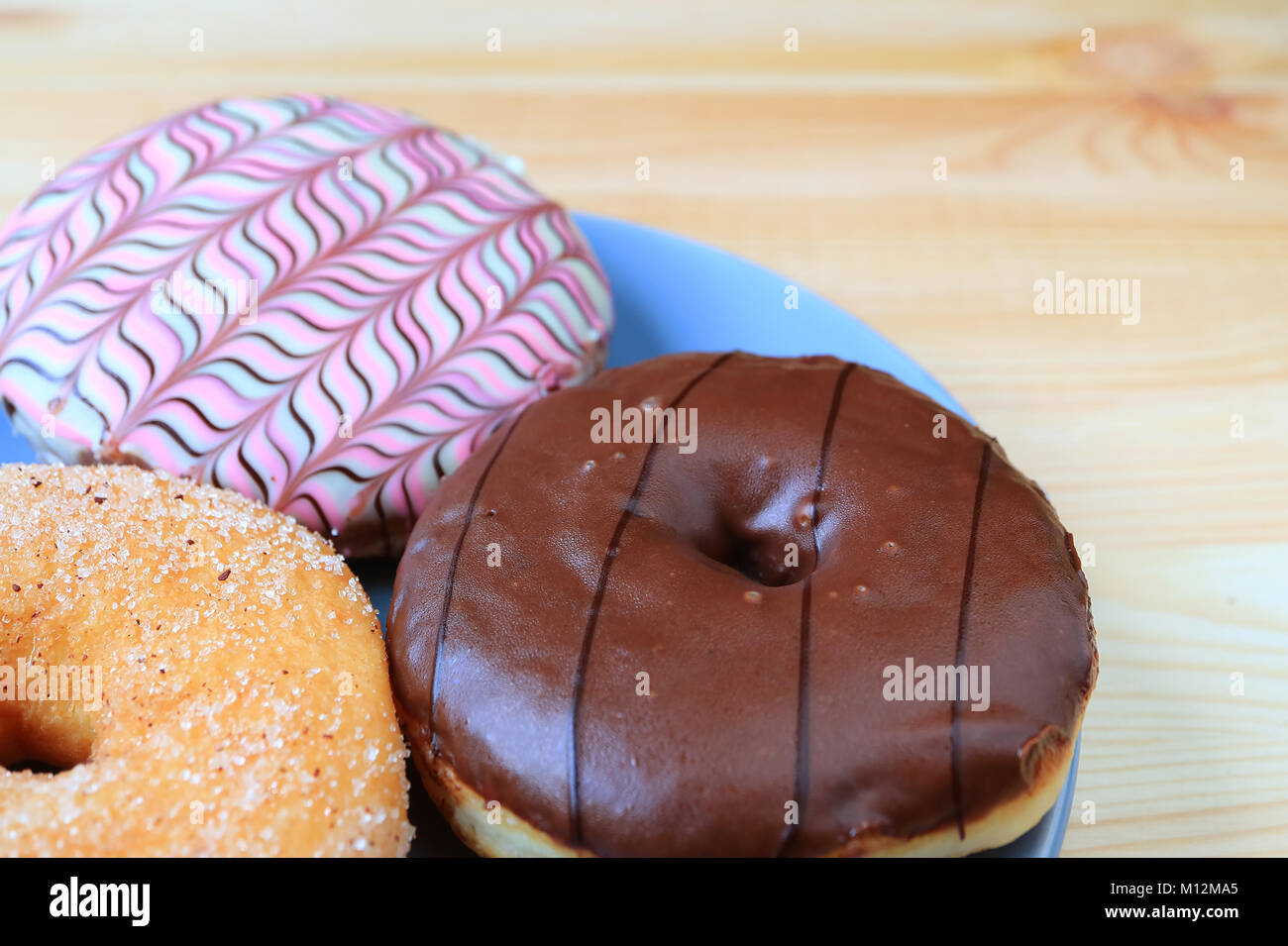 Geschlossen bis drei Arten von leckeren Donuts auf Holztisch mit selektiven Fokus serviert und unscharfen Hintergrund Stockfoto