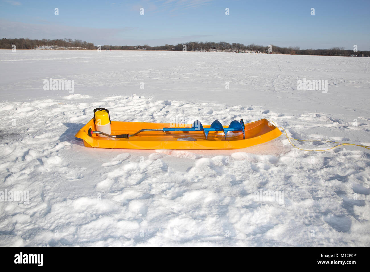 Eine gelbe Eisfischen Schlitten mit einem blauen Eis Schnecke (eine spiralförmige Schraube Blade) auf einem gefrorenen Minnesota See Stockfoto